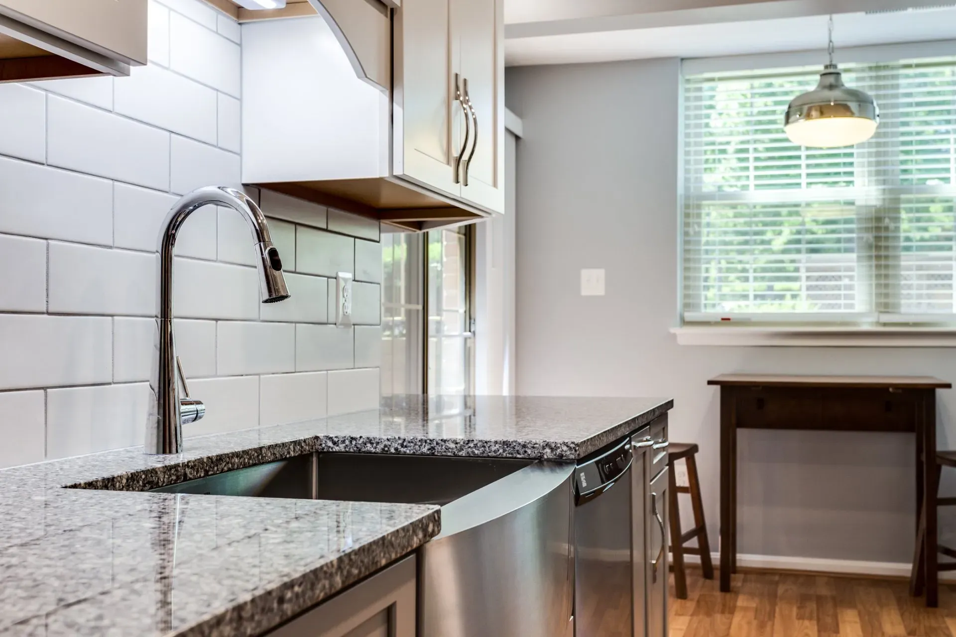 A kitchen with a sink , dishwasher , table and window.