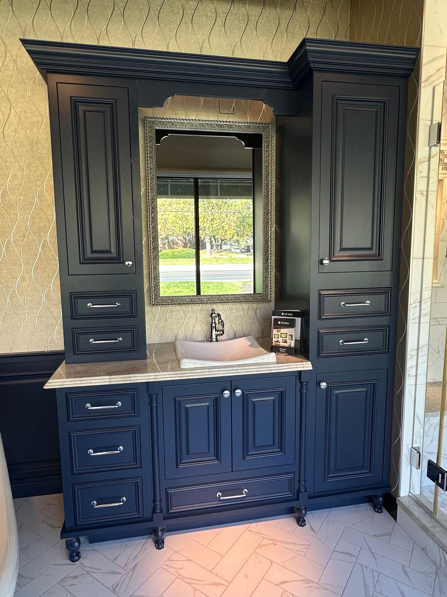 A bathroom with black cabinets , drawers , a sink and a mirror.