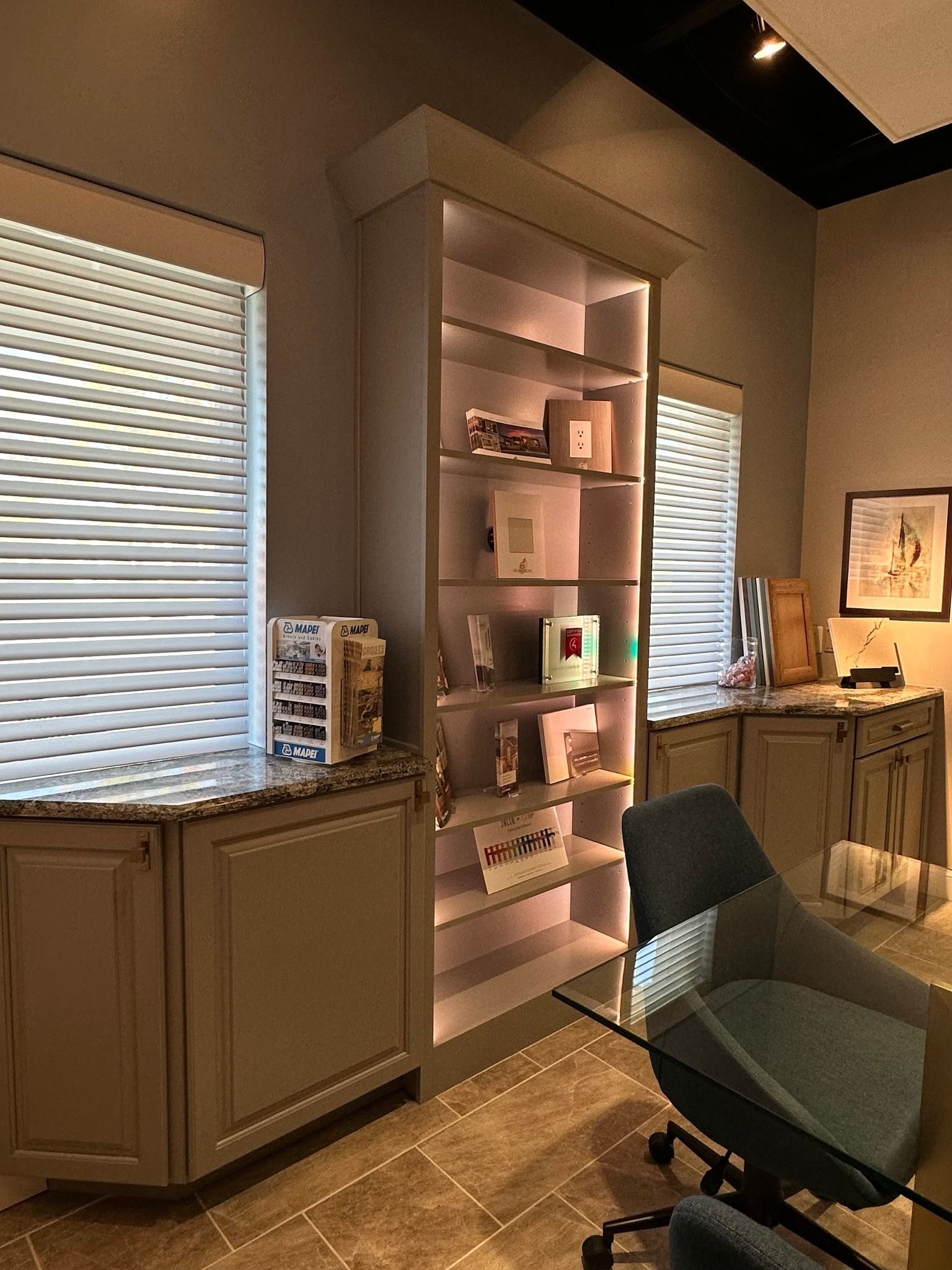 A room with a table , chairs , shelves , and blinds.