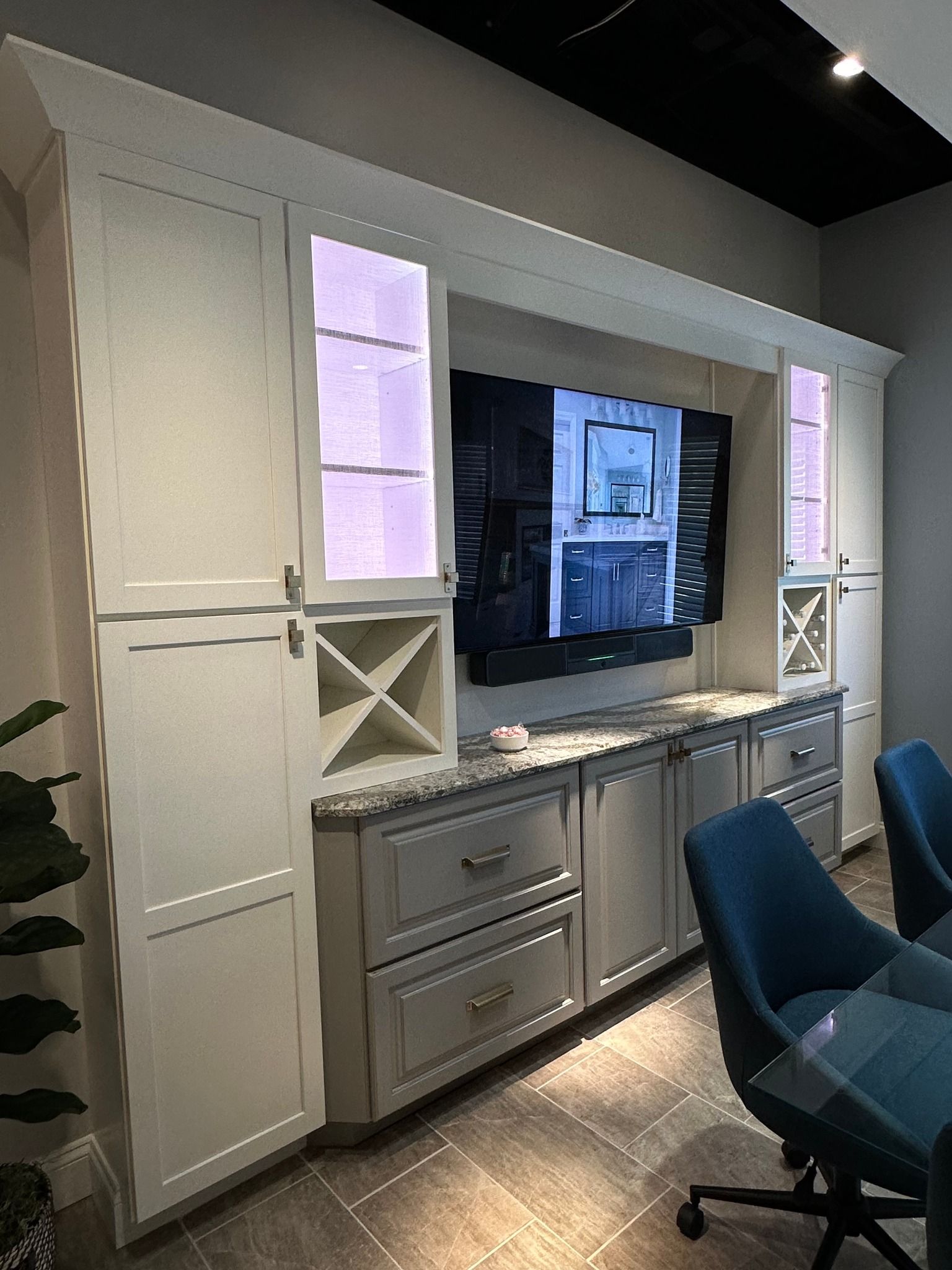 A kitchen with white cabinets and a flat screen tv on the wall.