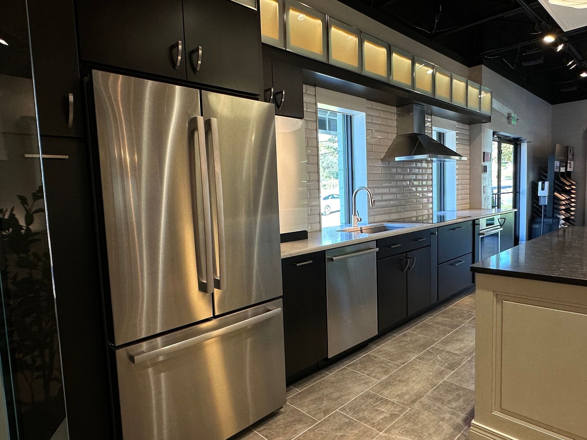 A kitchen with stainless steel appliances and black cabinets.