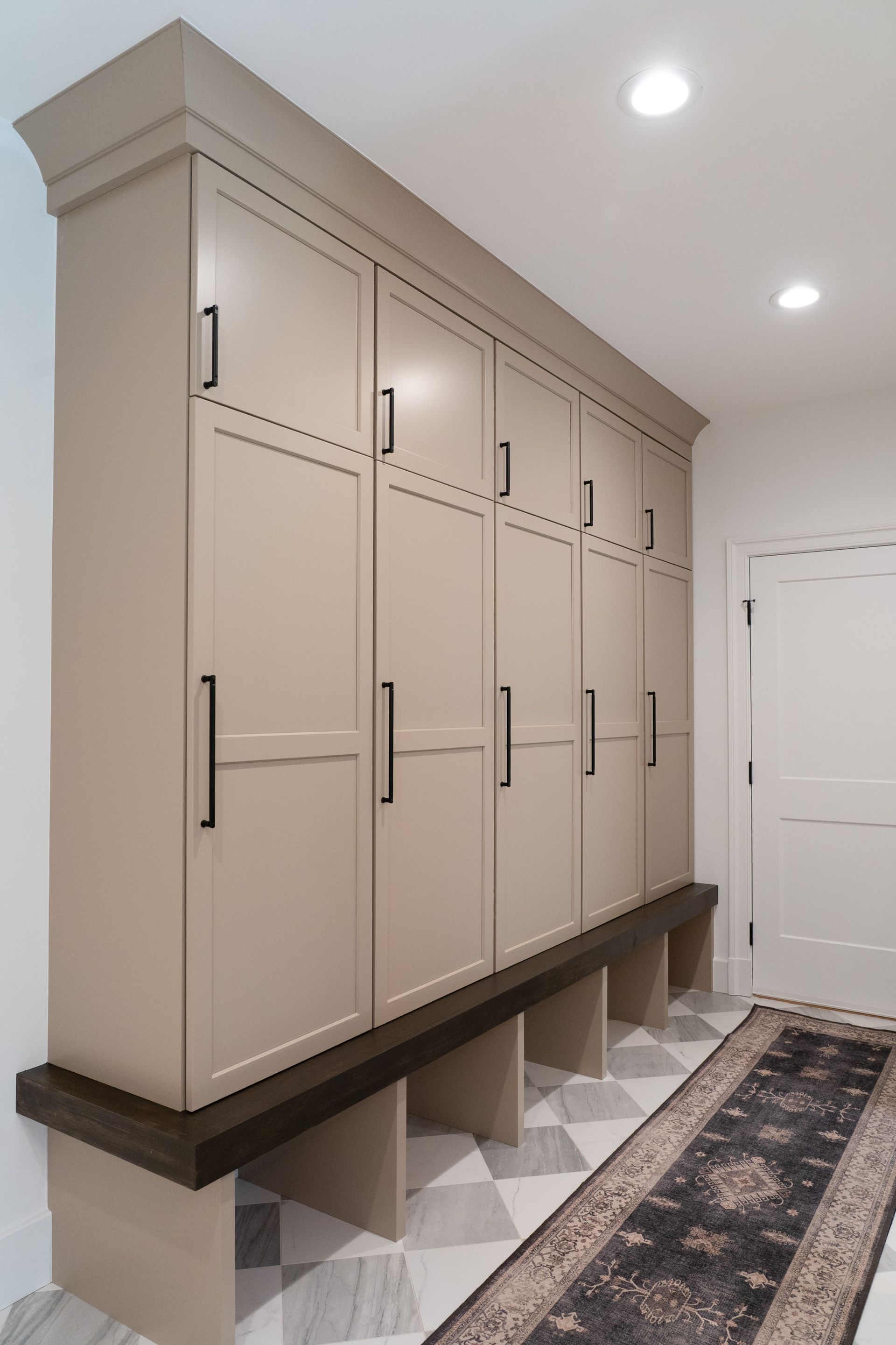 A hallway with a row of cabinets and a rug.