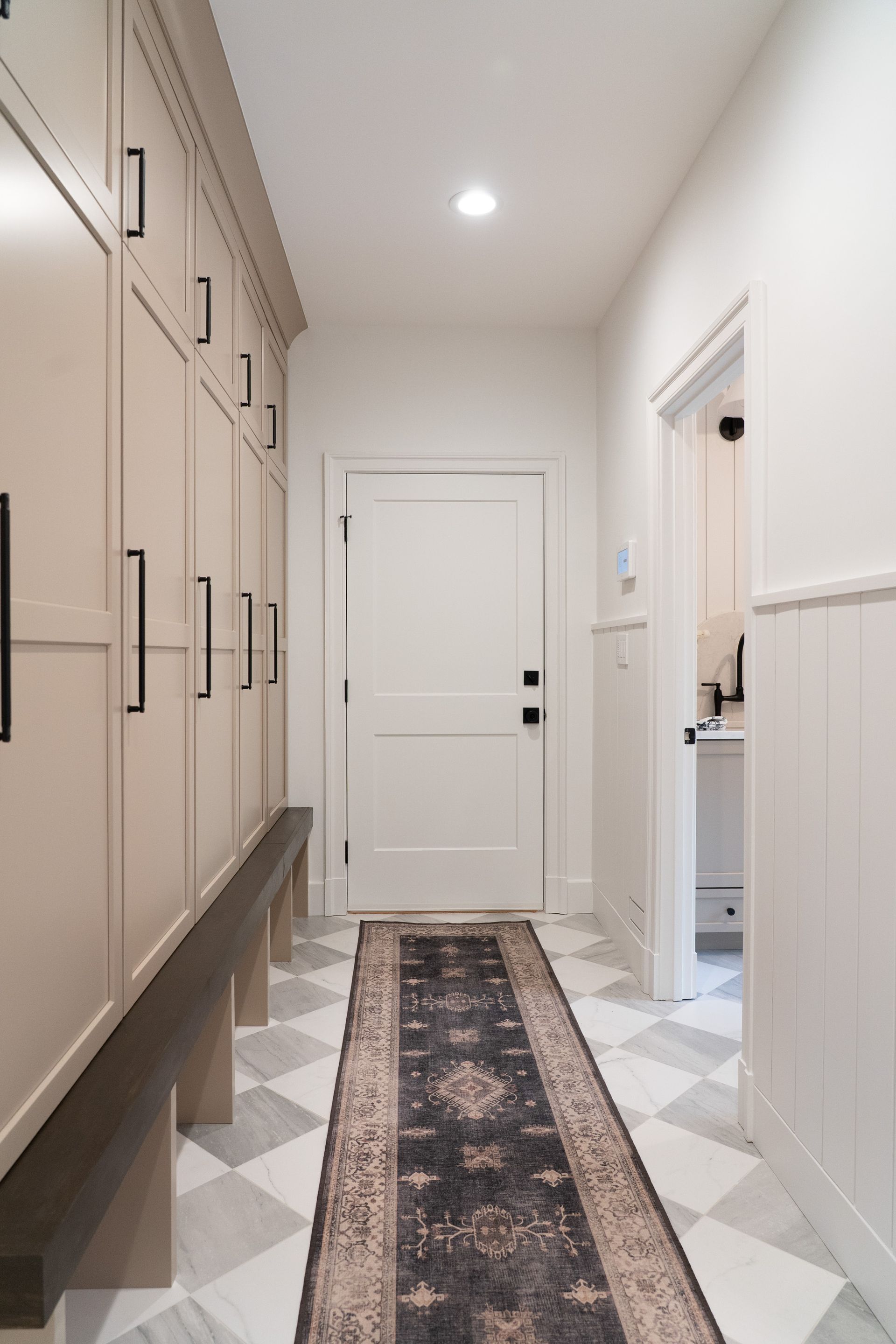 A hallway with a rug on the floor and a bench.