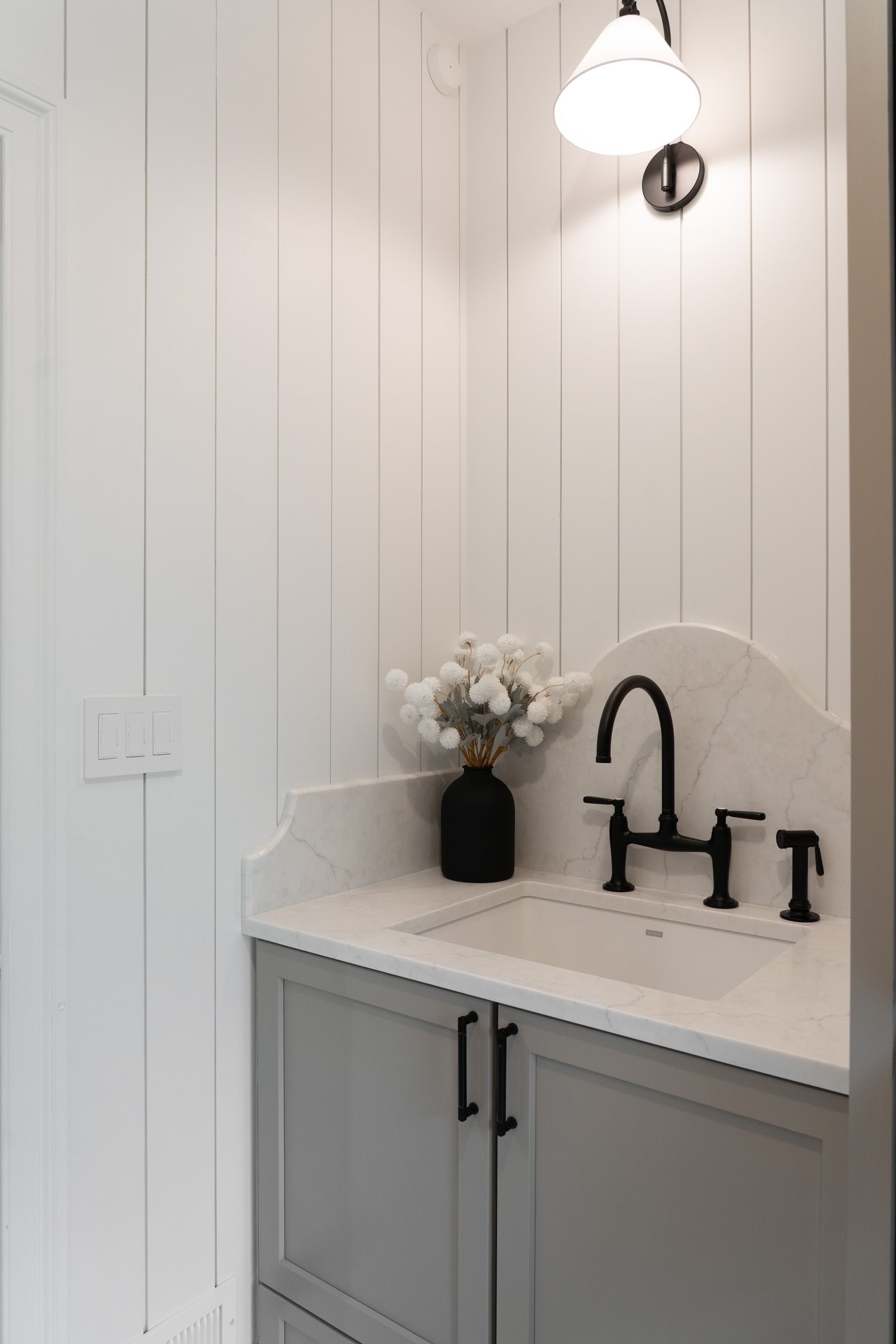 A bathroom with a sink and a vase of flowers on the counter.