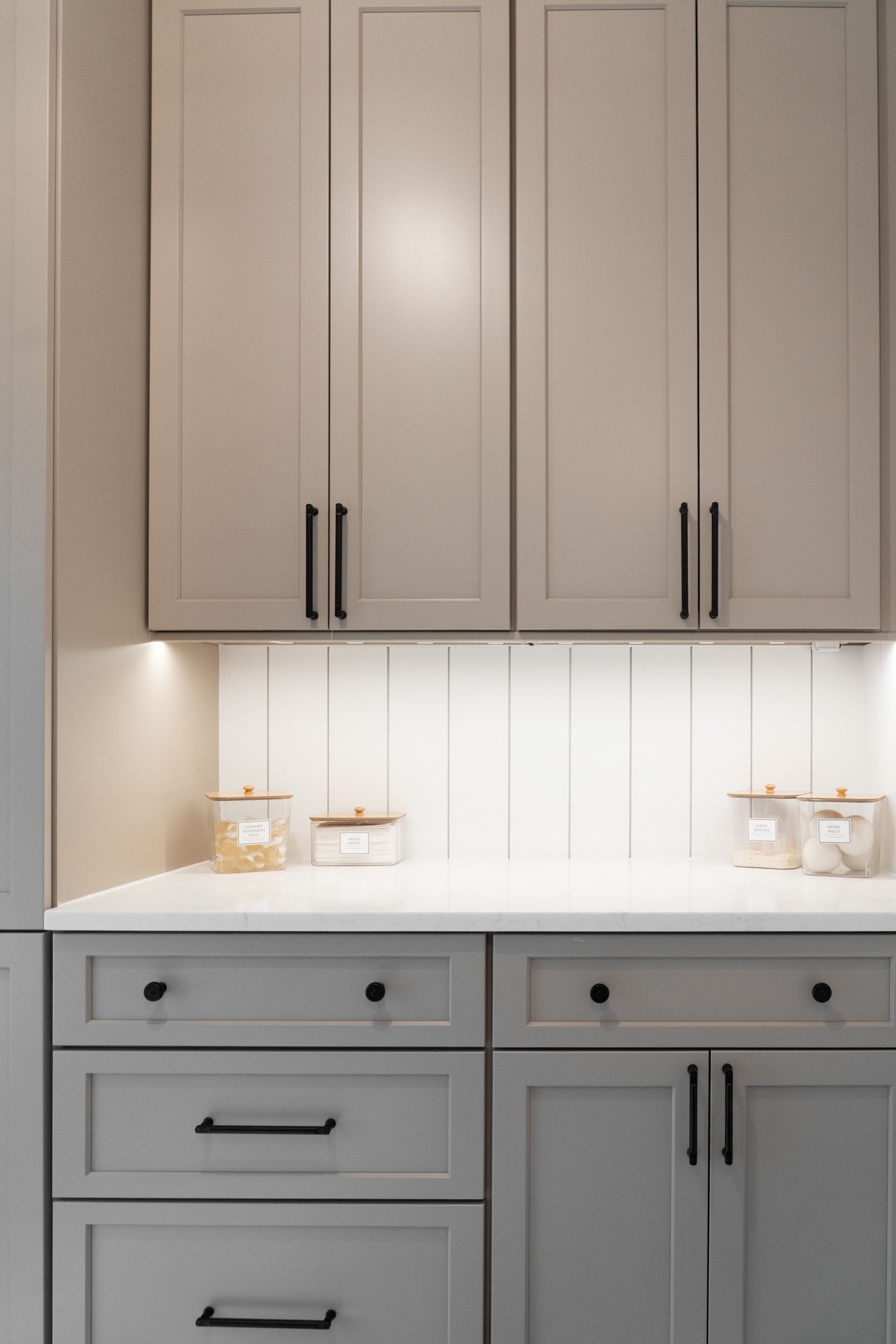 A kitchen with gray cabinets and white counter tops.