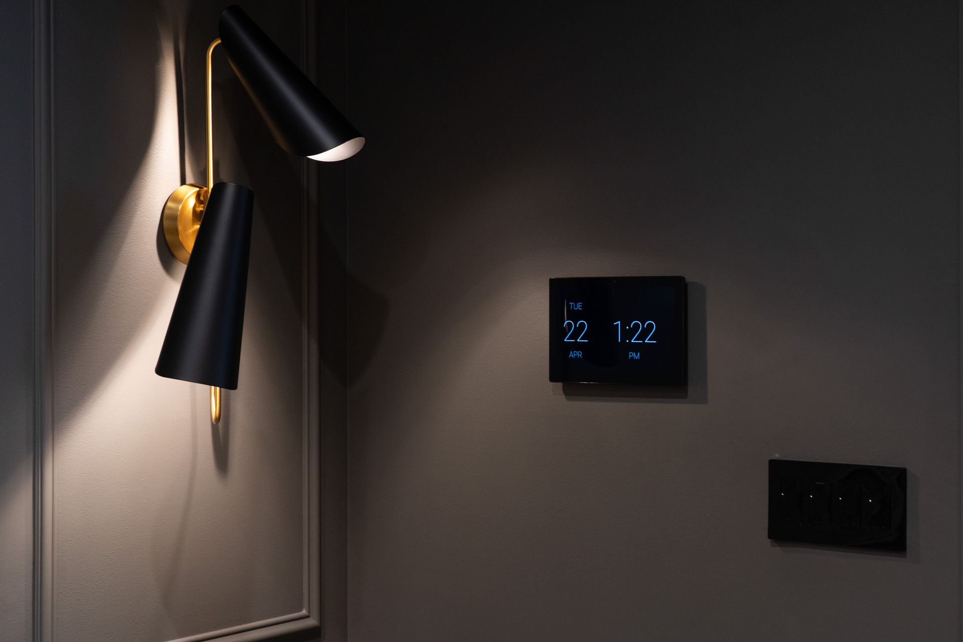 There is a lamp on the wall and a thermostat on the wall.