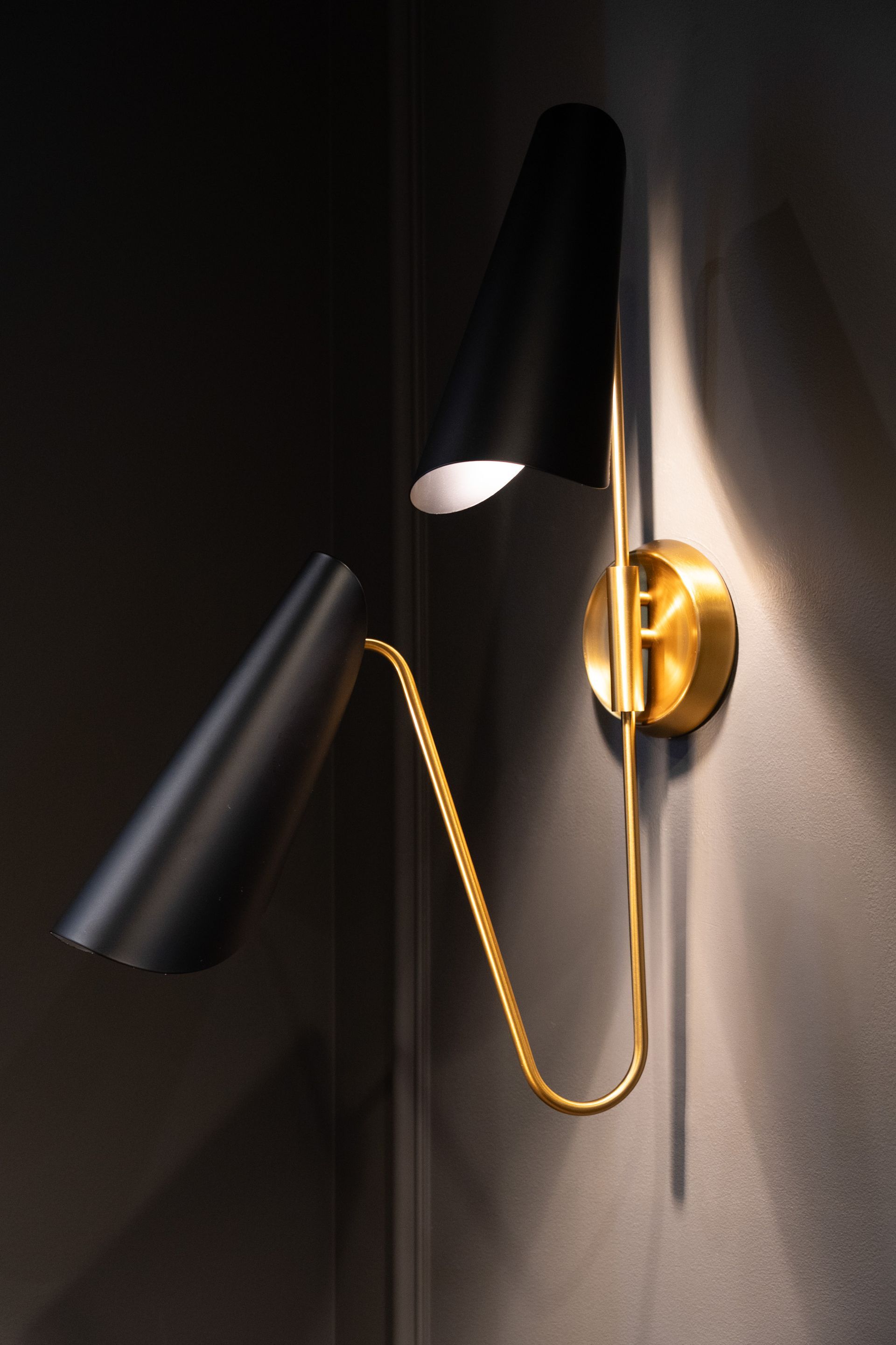 A black and gold wall light is on a dark wall