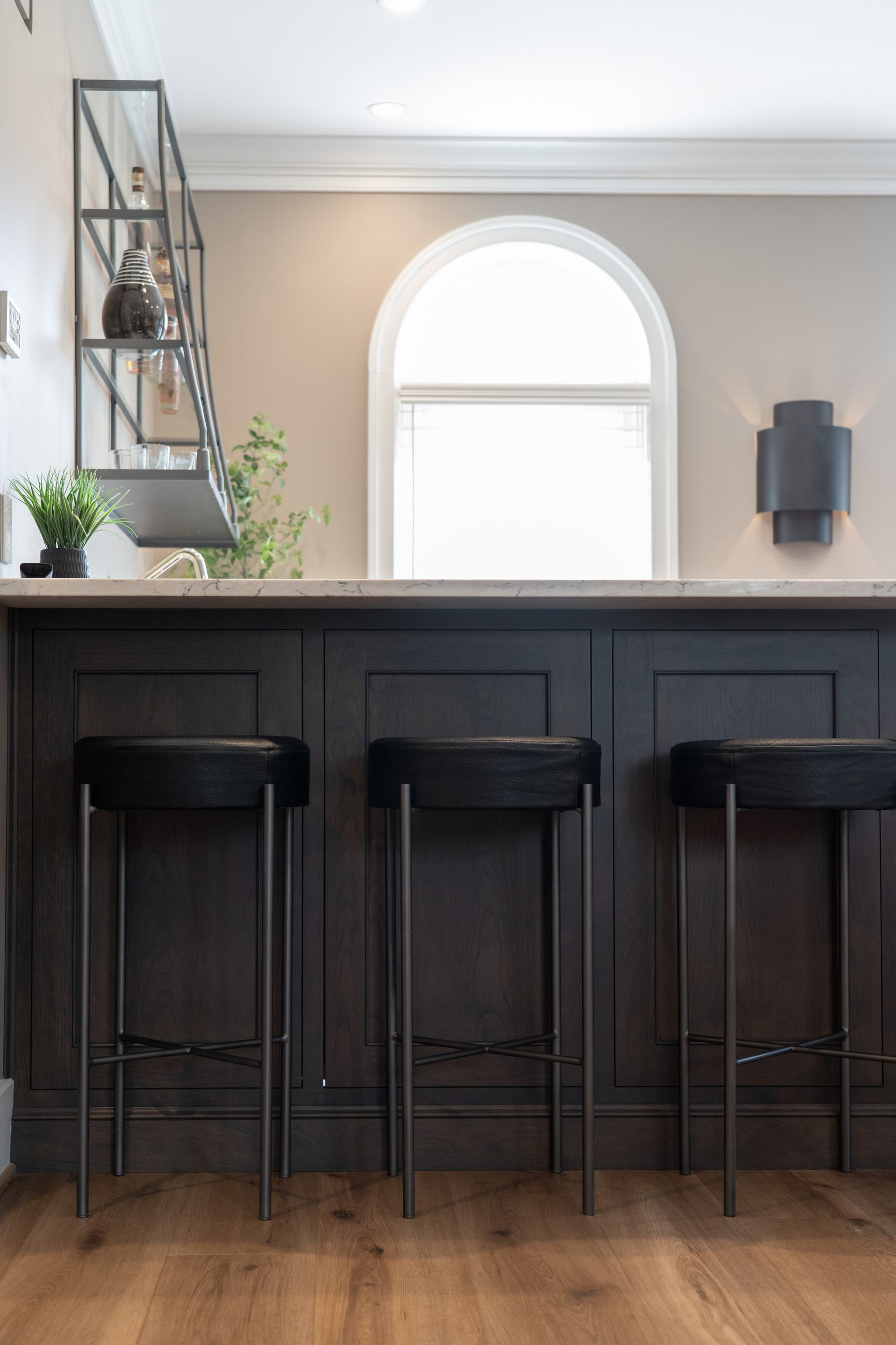 A kitchen with three bar stools and a window.
