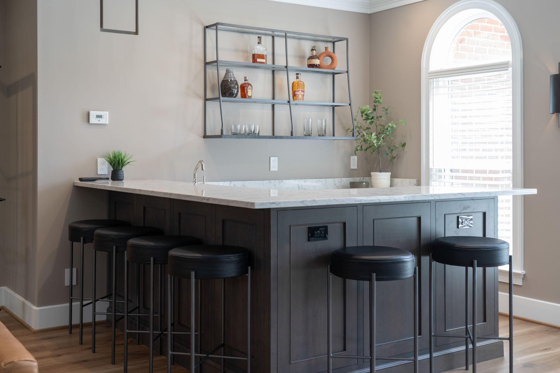 A kitchen with a bar and stools and a window.