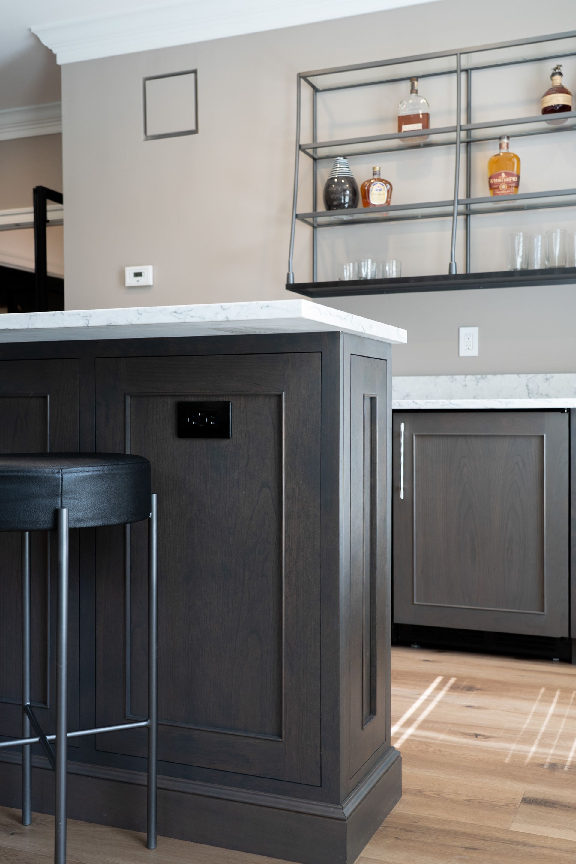 A kitchen with a bar and a shelf with bottles on it