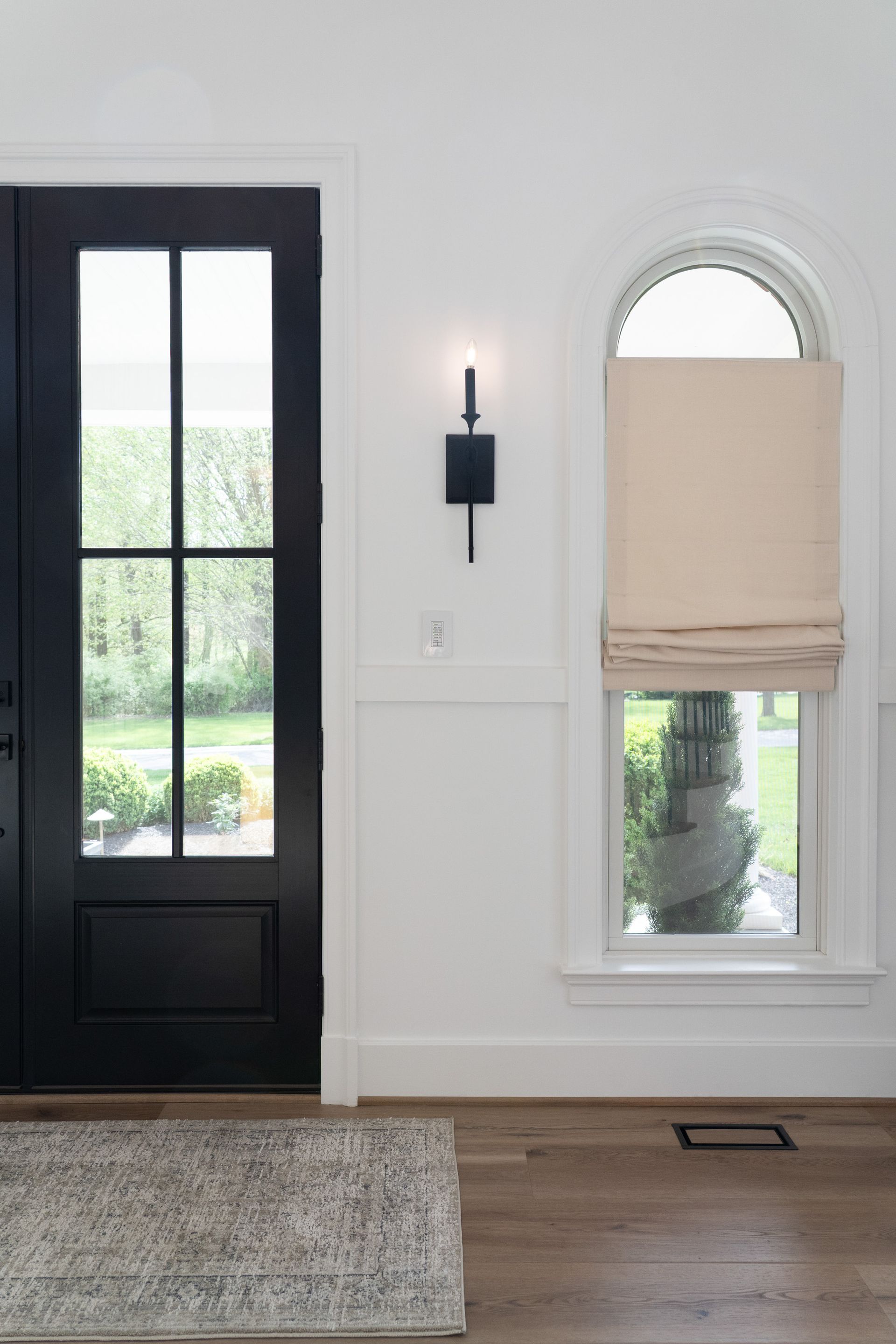 There is a black door and two windows in the room.