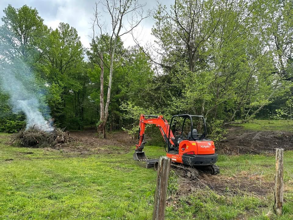 A red excavator is driving through a grassy field.