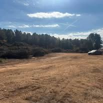 There is a car parked in the middle of a dirt road.