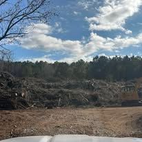 A large pile of wood is sitting in the middle of a dirt field.