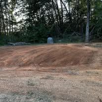 A dirt road in the middle of a forest with trees in the background.