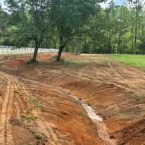 A dirt road going through a field with trees in the background.