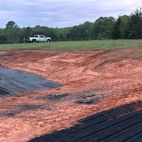 A white truck is parked in the middle of a dirt field.