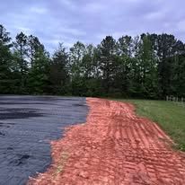 A dirt road going through a field with trees in the background.