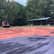 A bulldozer is moving dirt in a field with trees in the background.
