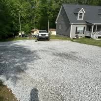 A truck is parked in a gravel driveway in front of a house.