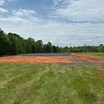 A baseball field with a lot of dirt in it and trees in the background.