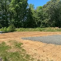 A dirt field with gravel and trees in the background.