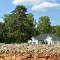 A house is sitting in the middle of a dirt field.