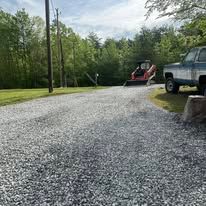 A truck is parked on the side of a gravel road.