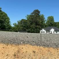 A gravel lot with a house in the background.