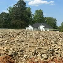 A large rocky field with a house in the background.