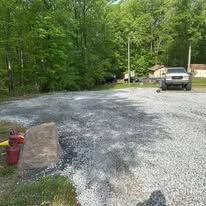 A truck is driving down a gravel road next to a fire hydrant.