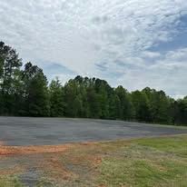 An empty parking lot with trees in the background on a sunny day.