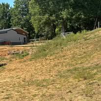 A large dry grass field with a house in the background.