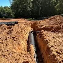 A pipe is being installed in a trench in the dirt.