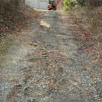 A dirt road leading to a garage with a tractor on it.
