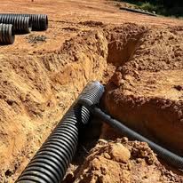 A drain pipe is being installed in a dirt field.
