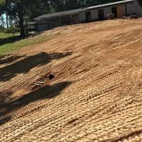 A dirt field with a house in the background.