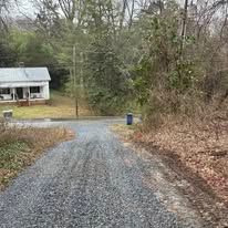 A gravel road leading to a house in the woods.