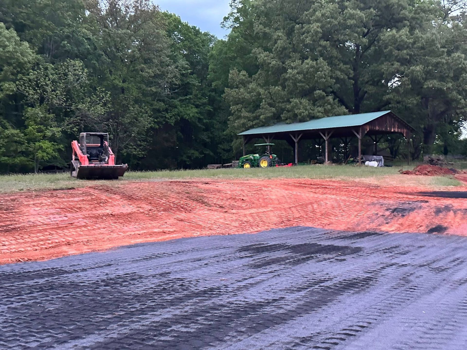 A bulldozer is moving dirt in a field with a pavilion in the background.