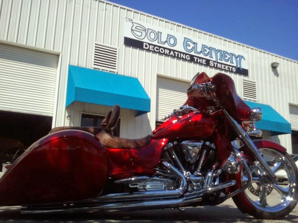 A red motorcycle is parked in front of a building that says solo element decorating the street