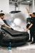 Two men are wrapping a car in a garage.