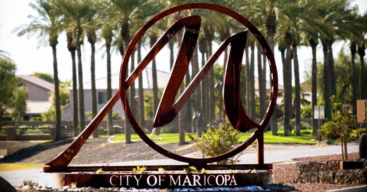 A city of maricopa sign with palm trees in the background
