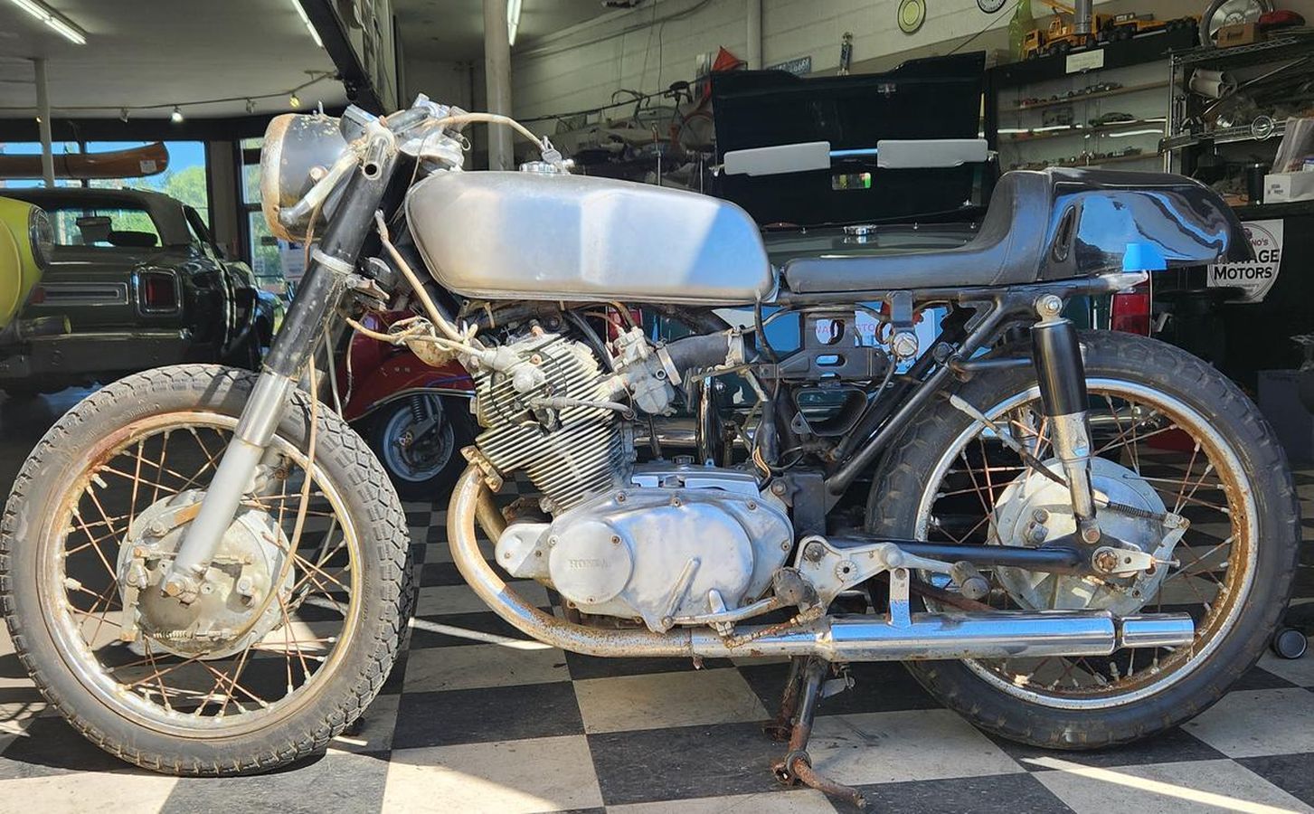 A motorcycle is sitting on a checkered floor in a garage.