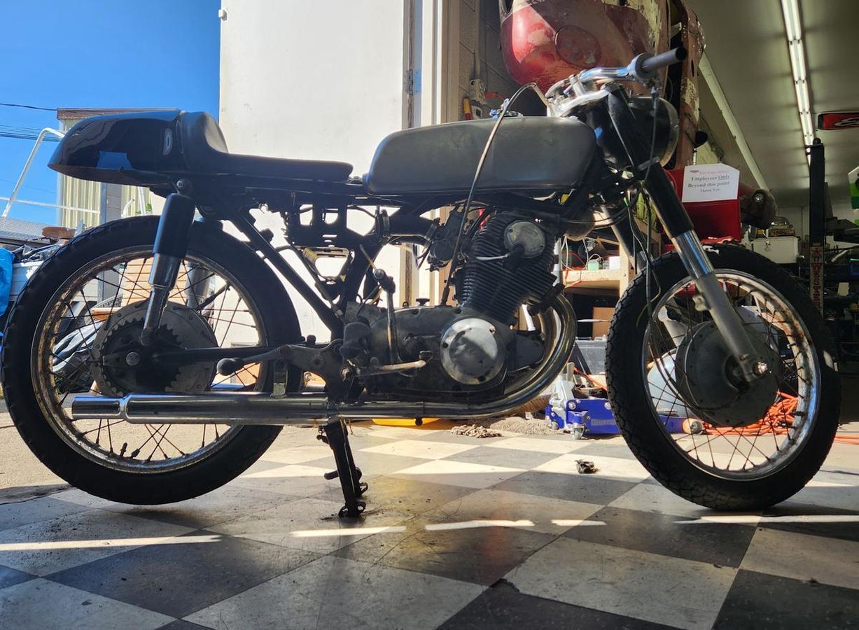 A motorcycle is parked on a checkered floor in a garage.