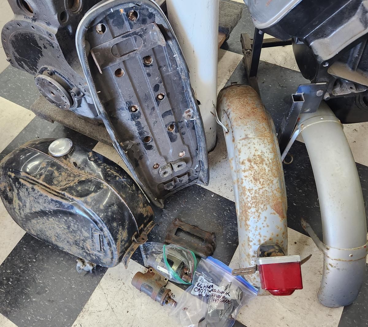 A bunch of motorcycle parts are laying on a checkered floor