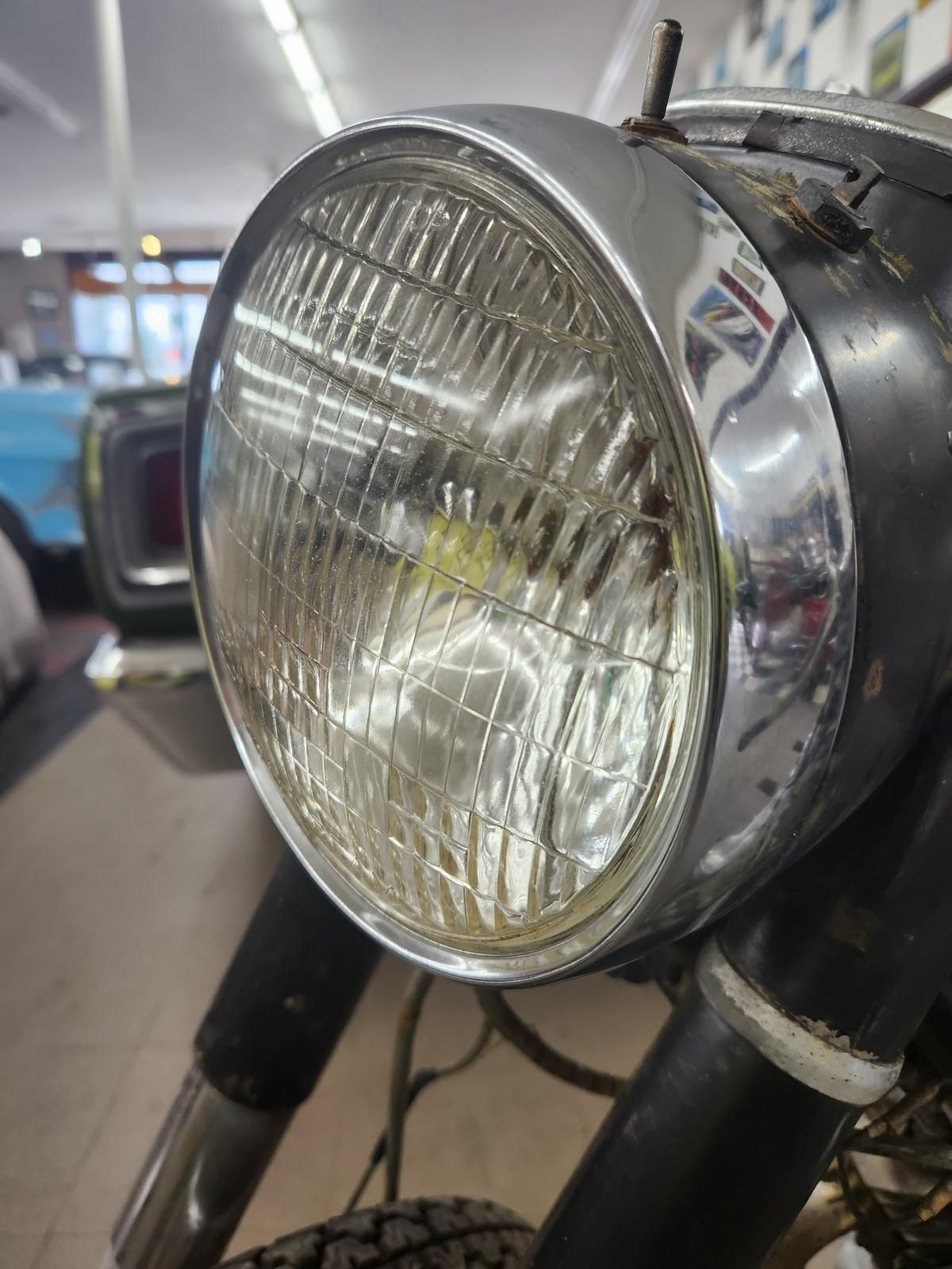 A close up of a motorcycle headlight in a garage.