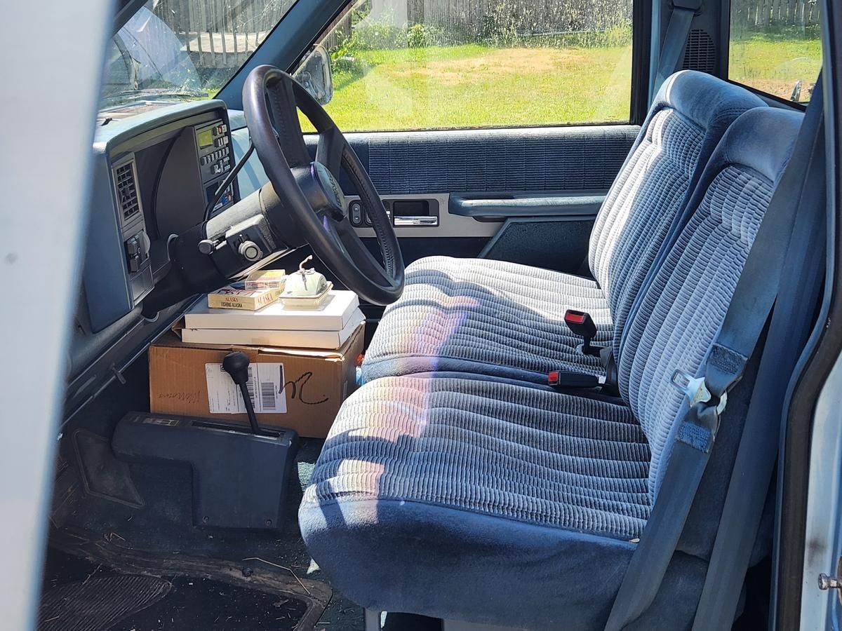 The inside of a blue truck with a steering wheel and seats