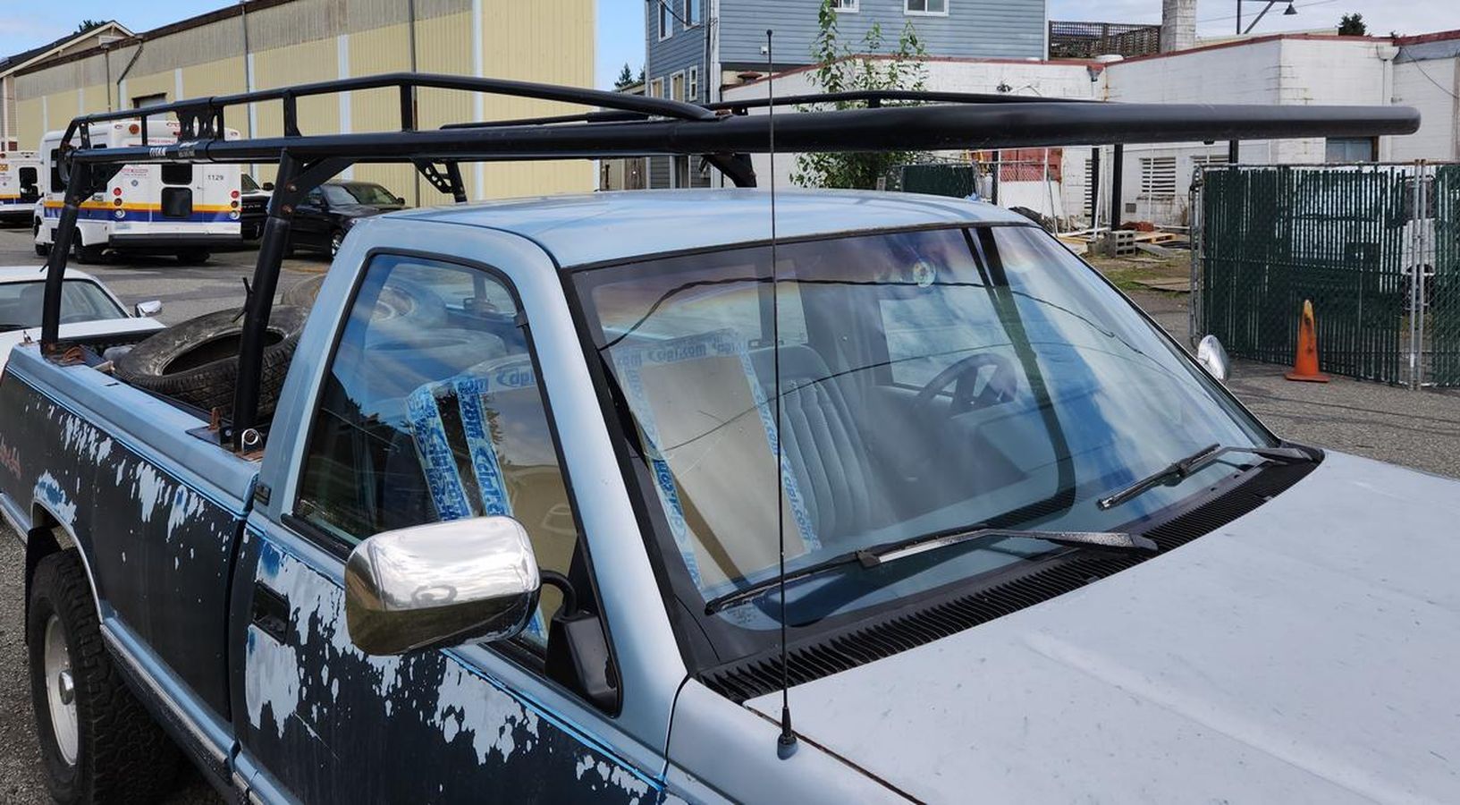 A truck with a surfboard rack on the roof is parked in a parking lot.