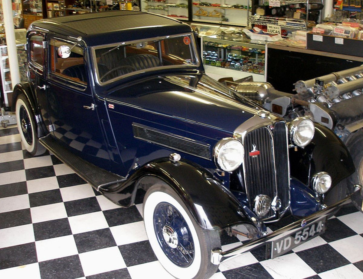 A blue car with white tires is parked on a checkered floor