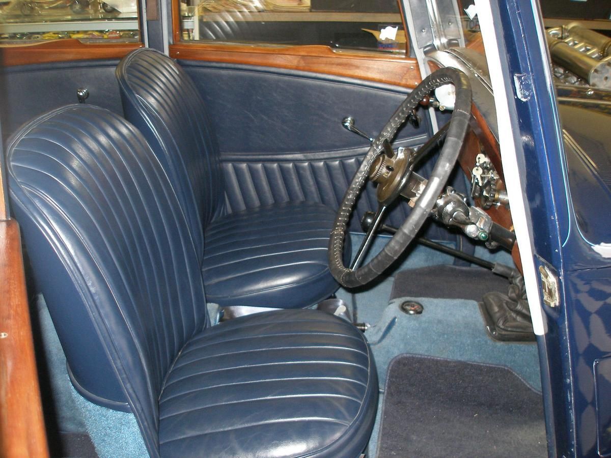 The interior of an old car with blue seats and a steering wheel